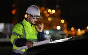 An electrical engineer communicates with his team via walkie-talkie at night